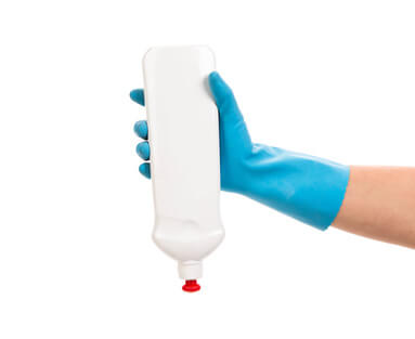Hand in gloves holds bottle.